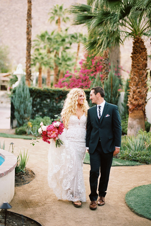  bride in a vintage bohemian gown with beaded details and cape, groom in a green suit with a floral tie