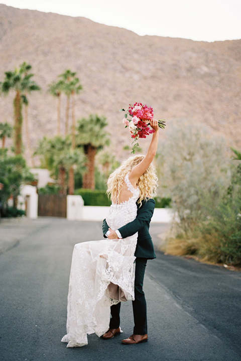  bride in a vintage bohemian gown with beaded details and cape, groom in a green suit with a floral tie