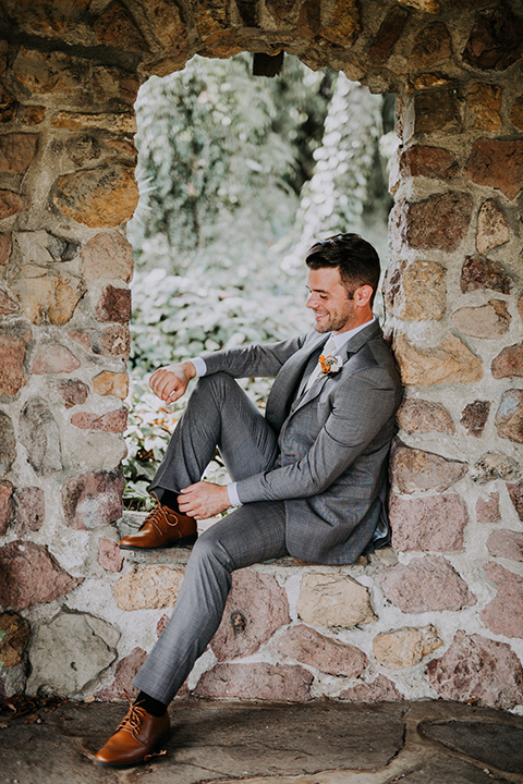  bride in a bohemian lace gown with a tulle skirt, lace boots, and headpiece and the groom in a café brown suit with an ivory tie, with a geometric arch 