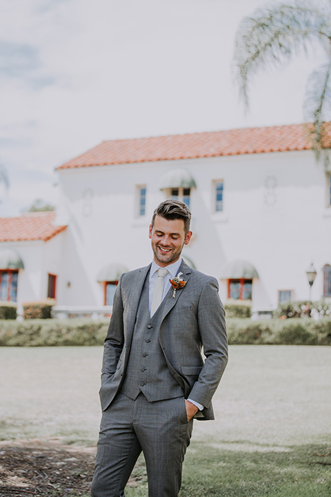  bride in a bohemian lace gown with a tulle skirt, lace boots, and headpiece and the groom in a café brown suit with an ivory tie, with a geometric arch