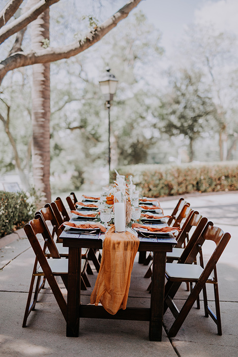  bride farmhouse table set up with white and orange linens and gold decor 