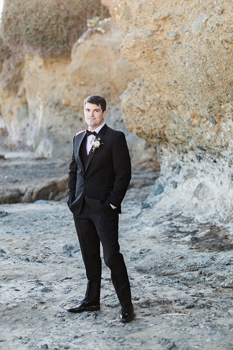  the groom in a black notch lapel tuxedo with a black bow tie 