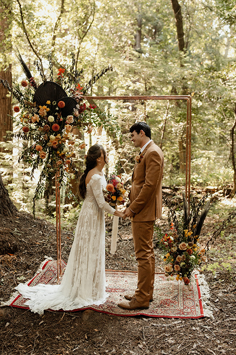  formfitting bridal lace gown with sleeves and the groom in a caramel suit with long tie 