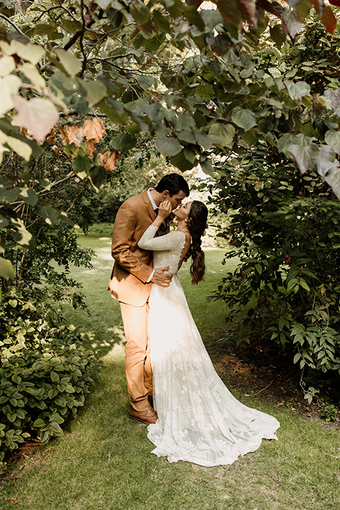  formfitting bridal lace gown with sleeves and the groom in a caramel suit with long tie