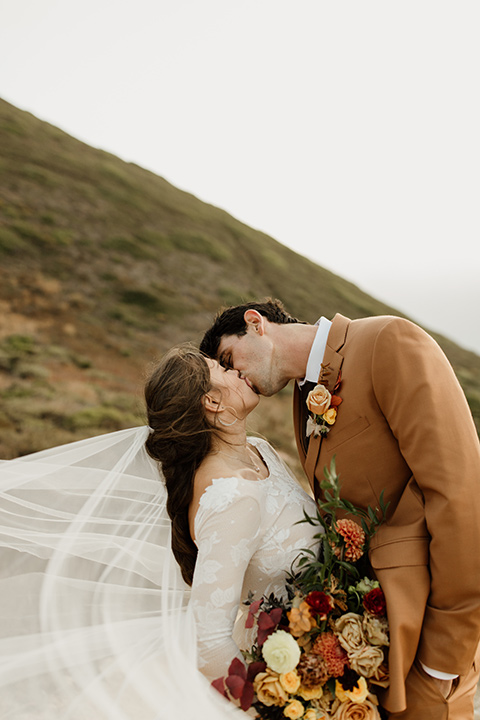  formfitting bridal lace gown with sleeves and the groom in a caramel suit with long tie 