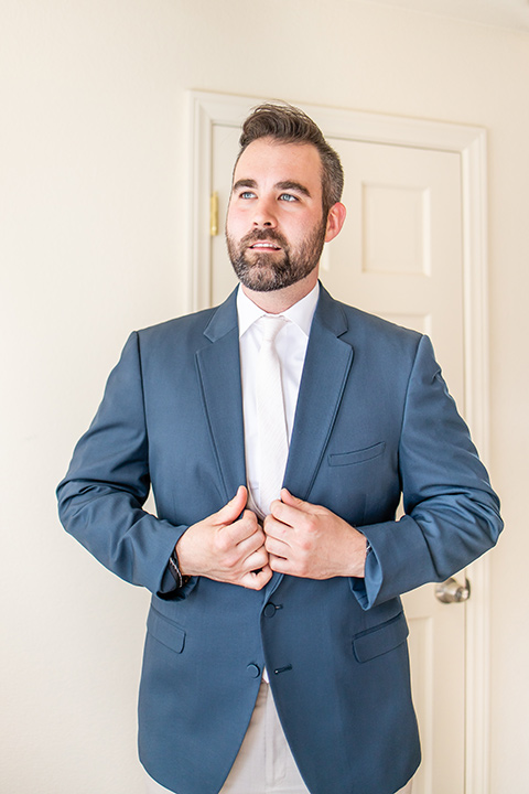  the groom in a blue suit coat and tan pants with a white long tie 