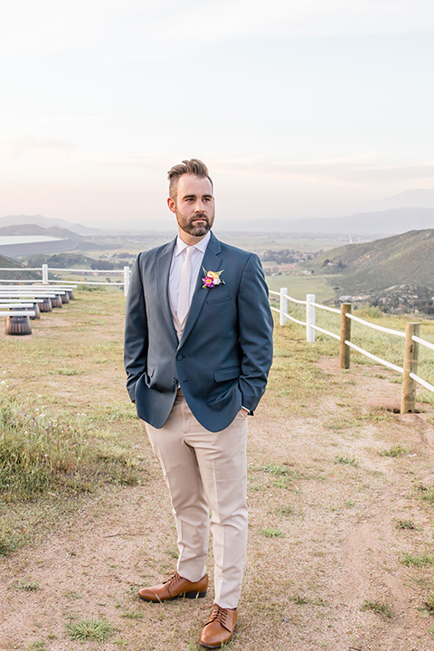  groom in a blue suit coat and tan pants with a white long tie 