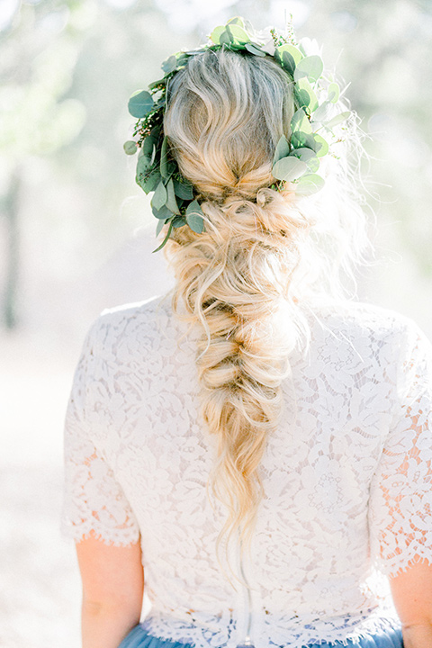 bride in a two-piece gown with a blue tulle skirt and white lace shirt and her hair in a loose French braid and floral crown