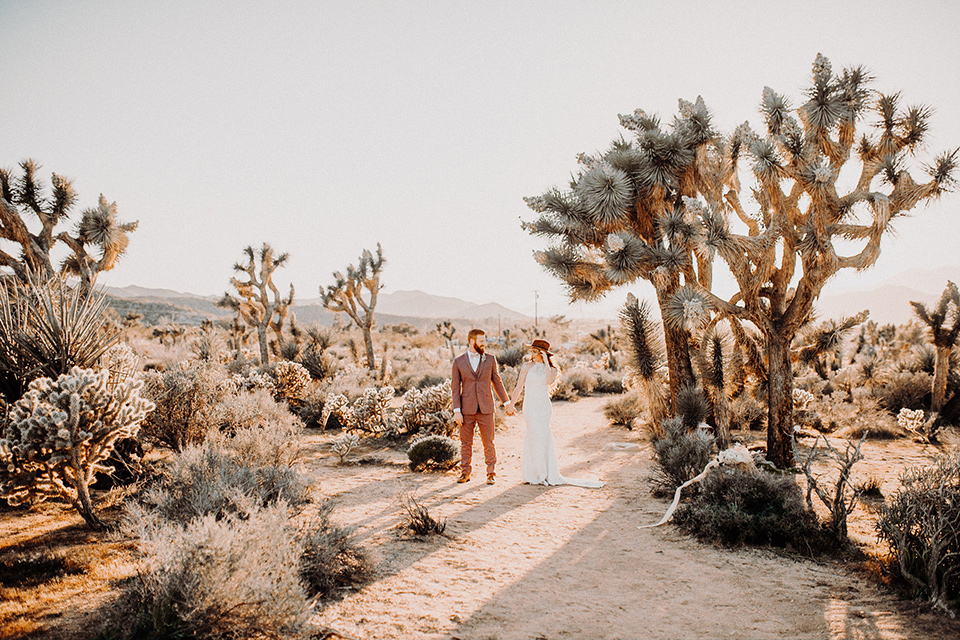  bride in a high neckline gown with lace details, groom in a rose pink suit with a bow tie 