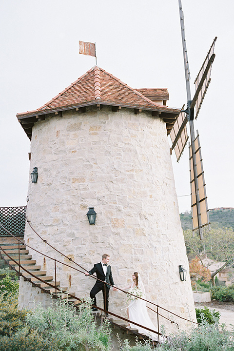  bride in a white lace ballgown with long sleeves and a v-neckline and the groom in a black tuxedo with a black bow tie and pocket square 