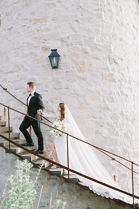  bride in a white lace ballgown with long sleeves and a v-neckline and the groom in a black tuxedo with a black bow tie and pocket square 
