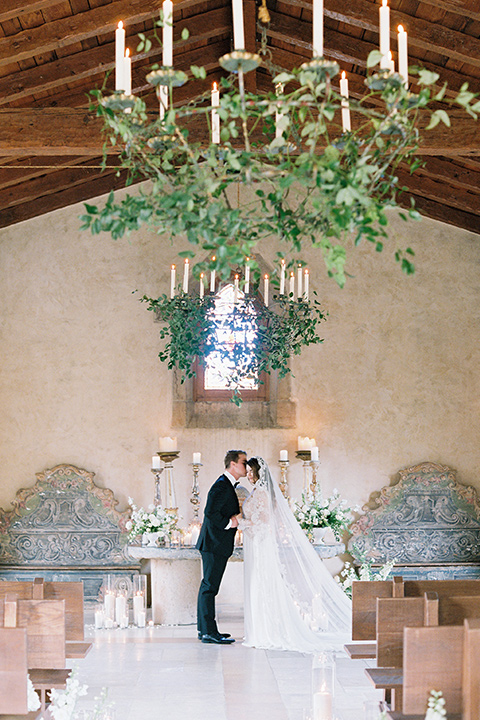  bride in a white lace ballgown with long sleeves and a v-neckline and the groom in a black tuxedo with a black bow tie and pocket square 