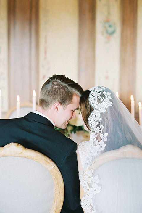  bride in a white lace ballgown with long sleeves and a v-neckline and the groom in a black tuxedo with a black bow tie and pocket square 