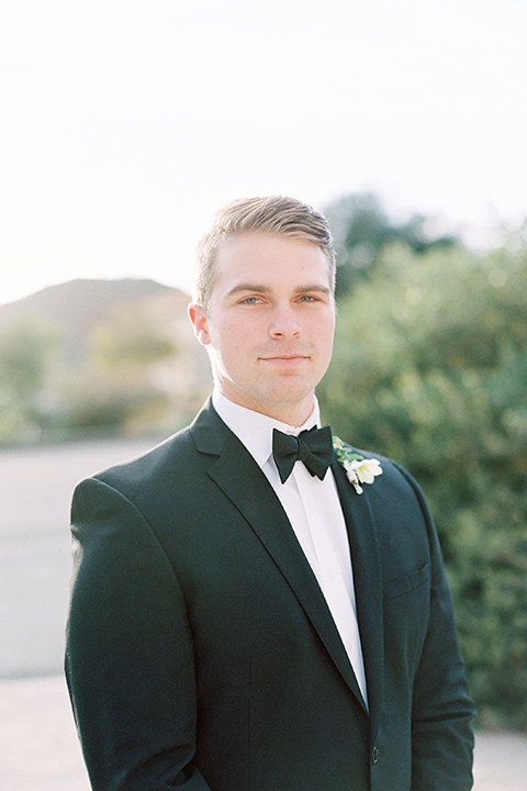  groom in a black tuxedo with a black bow tie and pocket square 