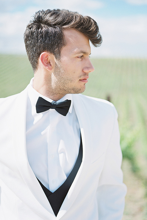 the groom in a white dinner jacket and black pants 