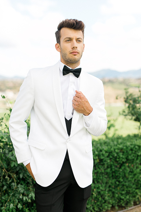  the groom in a white dinner jacket and black pants 