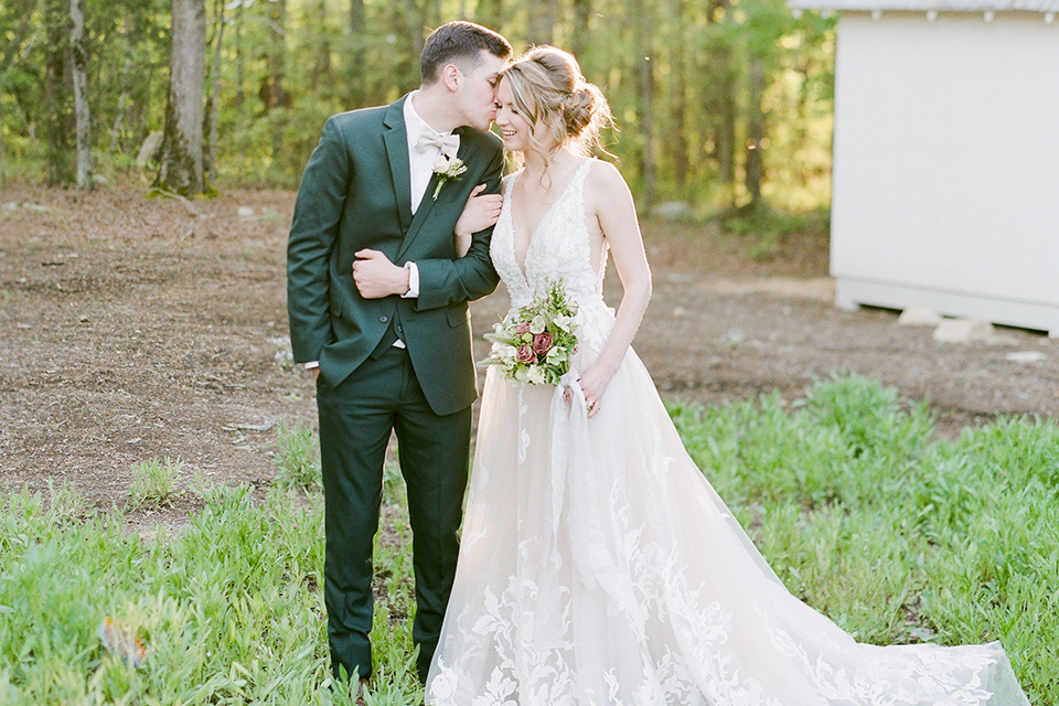  groom in a green suit with a platinum bow tie and the bride in a white lace gown