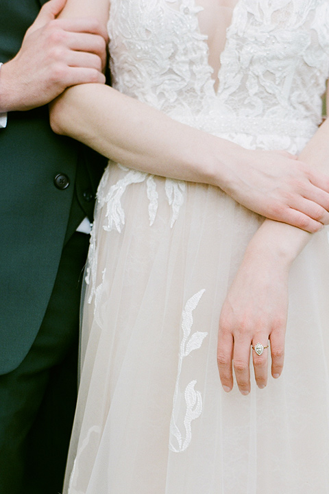  groom in a green suit with a grey bow tie and the bride in an ivory lace gown with an illusion neck line, close up