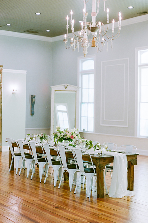  wooden table with white farm chairs and green + white floral centerpieces