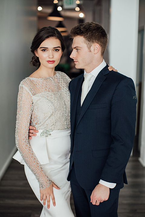  bride in a second gown with an illusion bodice and long sleeves with crystal detailing and a fitted skirt 