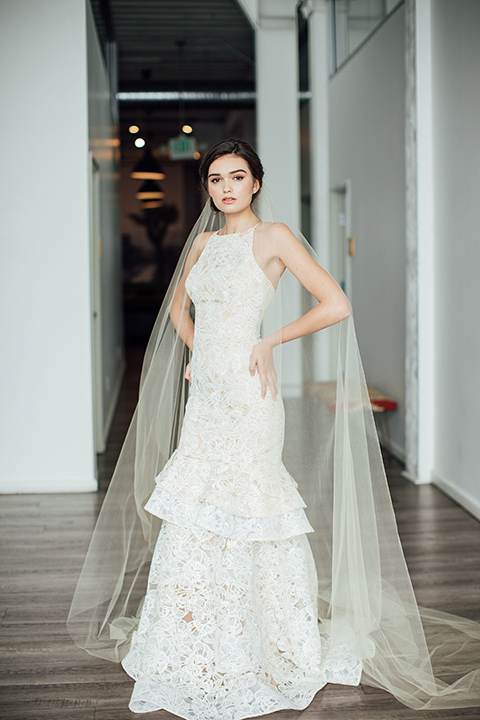  bride in a modern gown with a high neckline, no sleeves, and a tiered ruffled skirt 