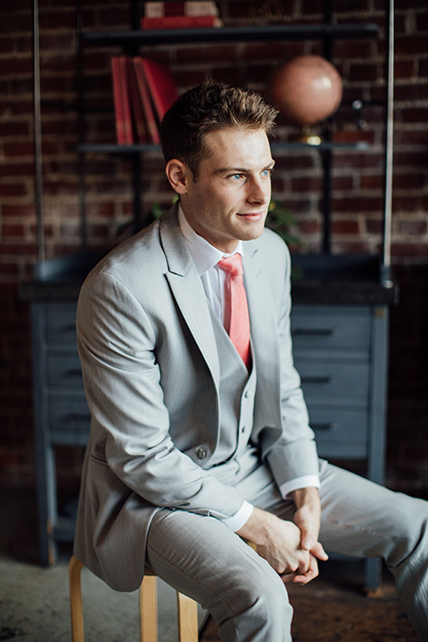  groom in a light grey suit with a coral tie 