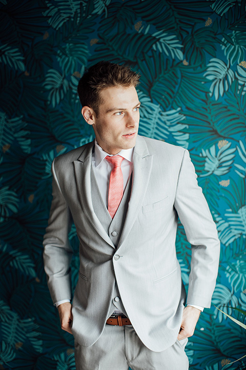  groom in a light grey suit with a coral tie 