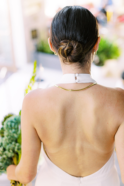  bride in a white gown with a low back design and her hair in a tight low bun 