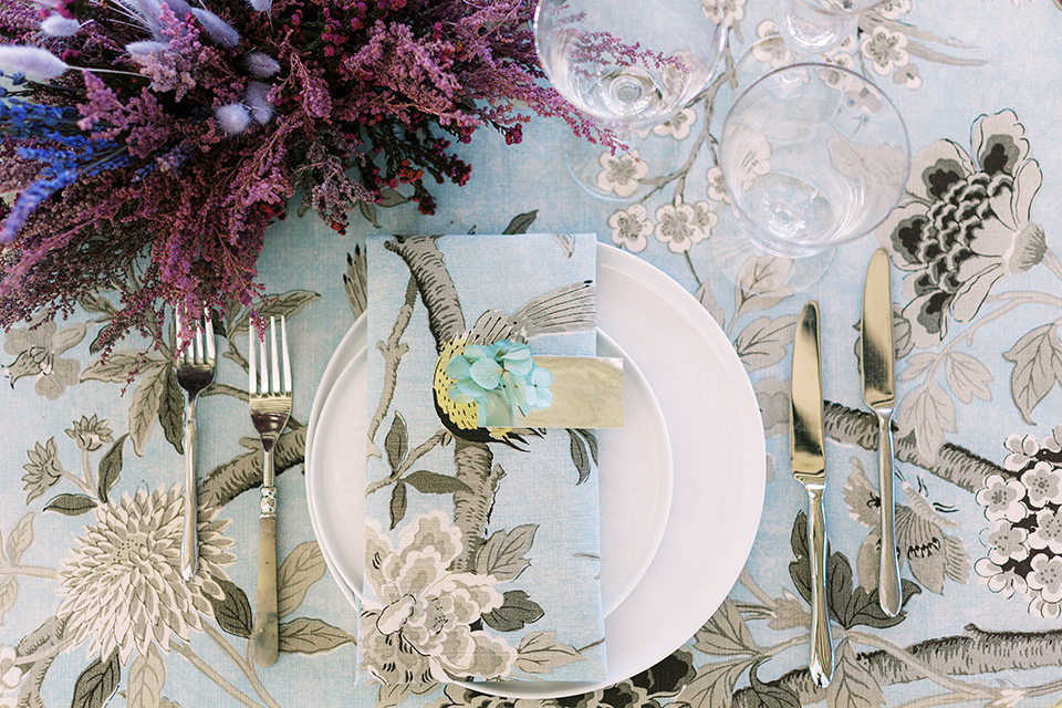  silver and blue floral tablecloth with white plates and silver flatware