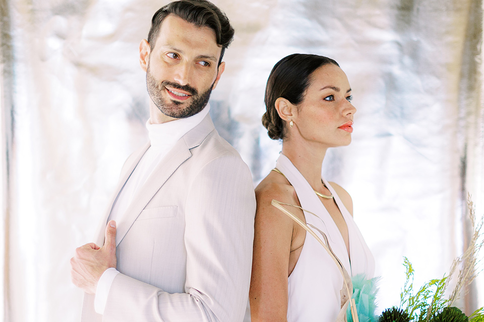  bride in a white jumpsuit with a halter and deep v neckline and her hair in a tight low bun with the city behind them 