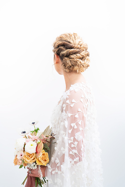  the bride in a lace white gown with long sleeves and a flowing skirt with hair in a modern low bun 