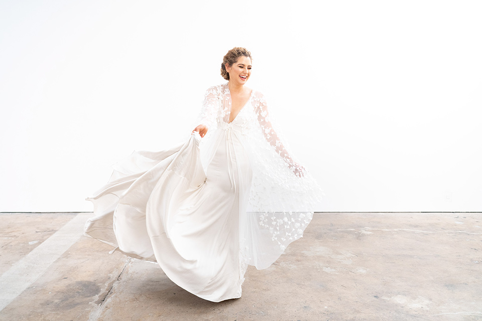  the bride in a lace white gown with long sleeves and a flowing skirt with hair in a modern low bun 