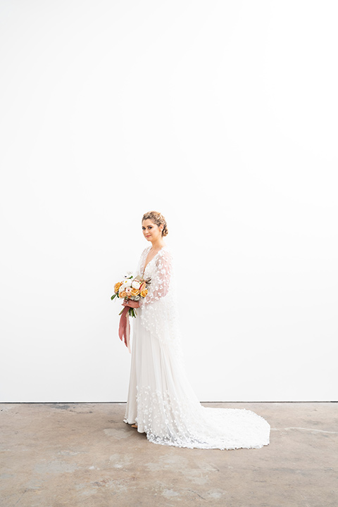  the bride in a lace white gown with long sleeves and a flowing skirt with hair in a modern low bun 