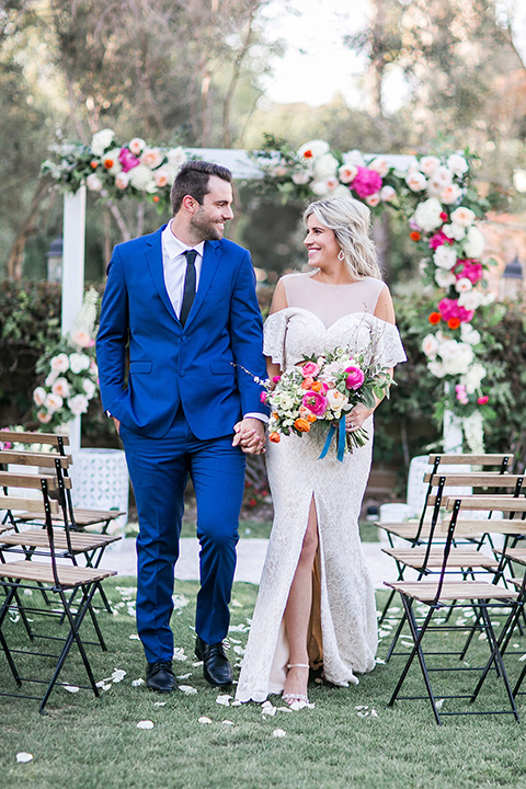  groom in a cobalt blue suit with a black long tie and brown shoes and the bride in a white bohemian gown with a high neckline and cold shoulder detail ceremony 