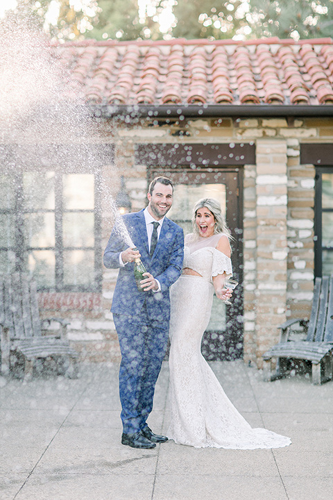  groom in a cobalt blue suit with a black long tie and brown shoes and the bride in a white bohemian gown with a high neckline and cold shoulder detail ceremony 