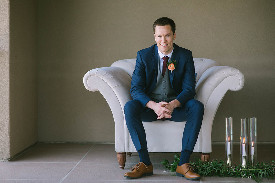  groom in a dark blue suit with a grey vest and burgundy long tie