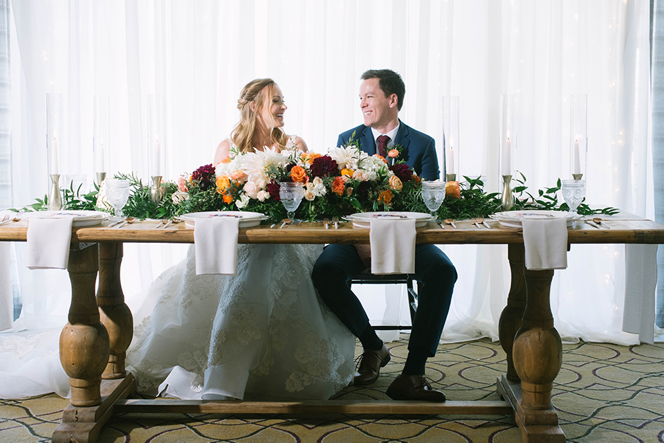  groom in a dark blue suit with a grey vest and burgundy long tie