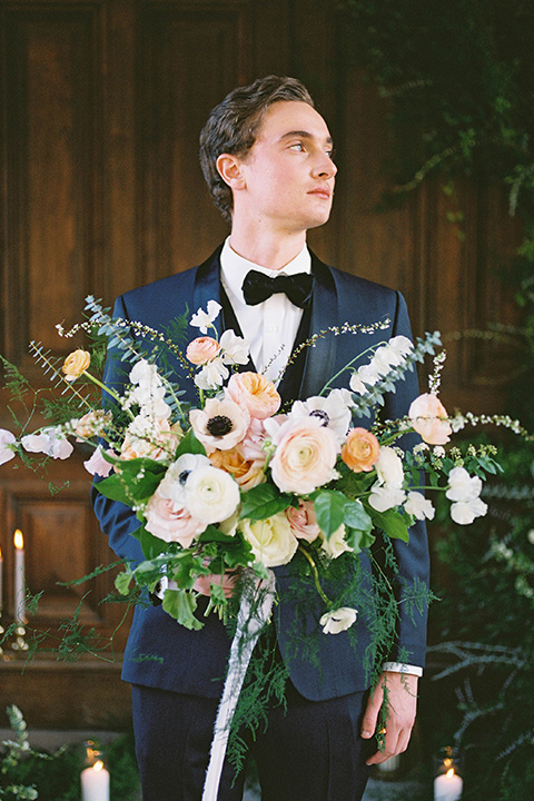  groom in a navy blue tuxedo with a black bow tie 