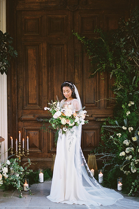  couple at ceremony groom in a navy blue tuxedo with a black bow tie and the bride in a white lace flowing gown and a long cathedral veil