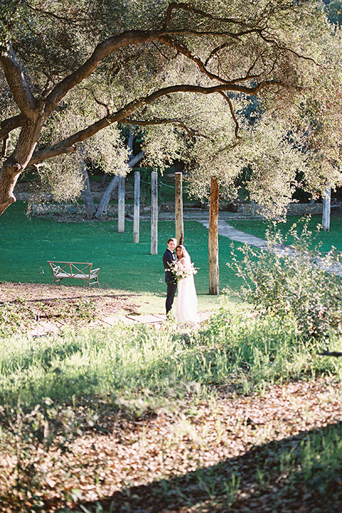  couple at ceremony groom in a navy blue tuxedo with a black bow tie and the bride in a white lace flowing gown and a long cathedral veil