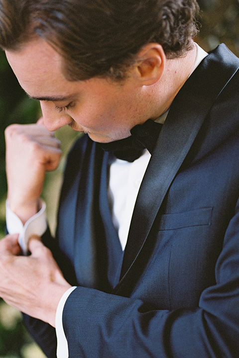  groom in a navy blue tuxedo with a black bow tie