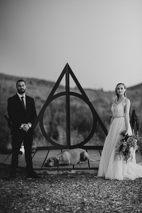  bride in a tulle a line gown with a sweetheart neckline and a crystal bodice and the groom in a black velvet tuxedo and black bow tie by ceremony altar 