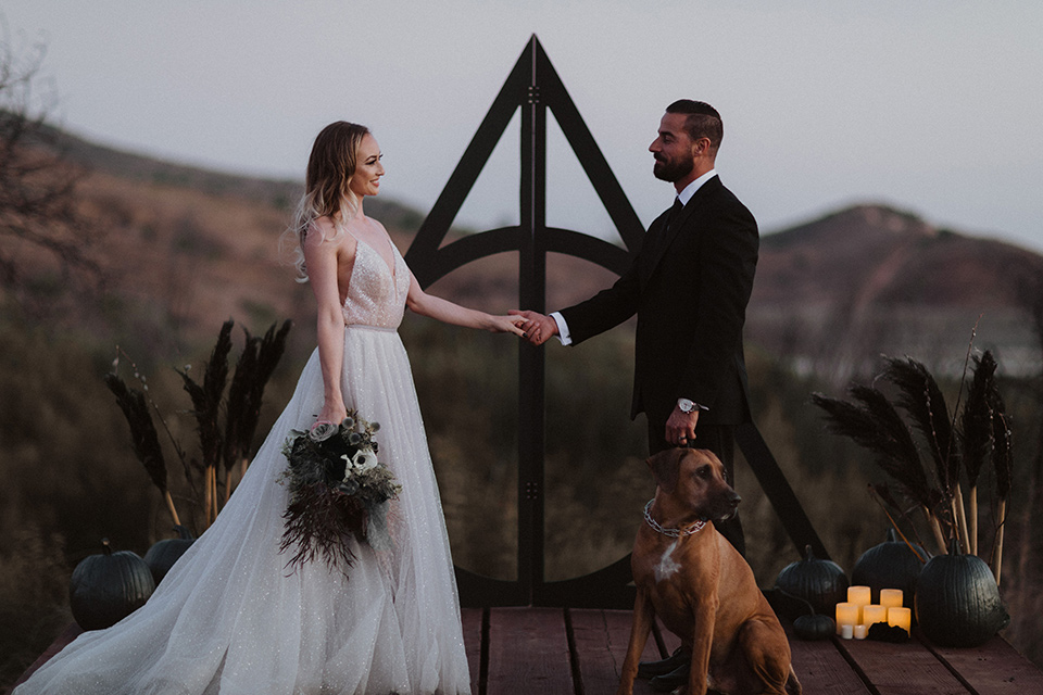  bride in a tulle a line gown with a sweetheart neckline and a crystal bodice and the groom in a black velvet tuxedo and black bow tie sitting at table