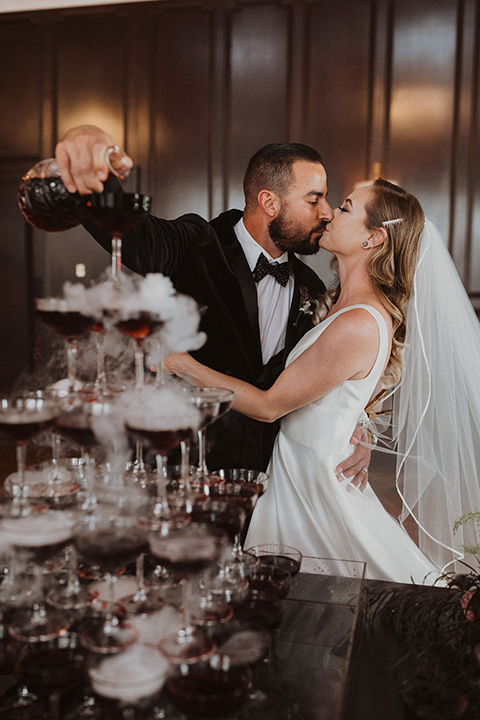  bride in a tulle a line gown with a sweetheart neckline and a crystal bodice and the groom in a black velvet tuxedo and black bow tie by champagne 