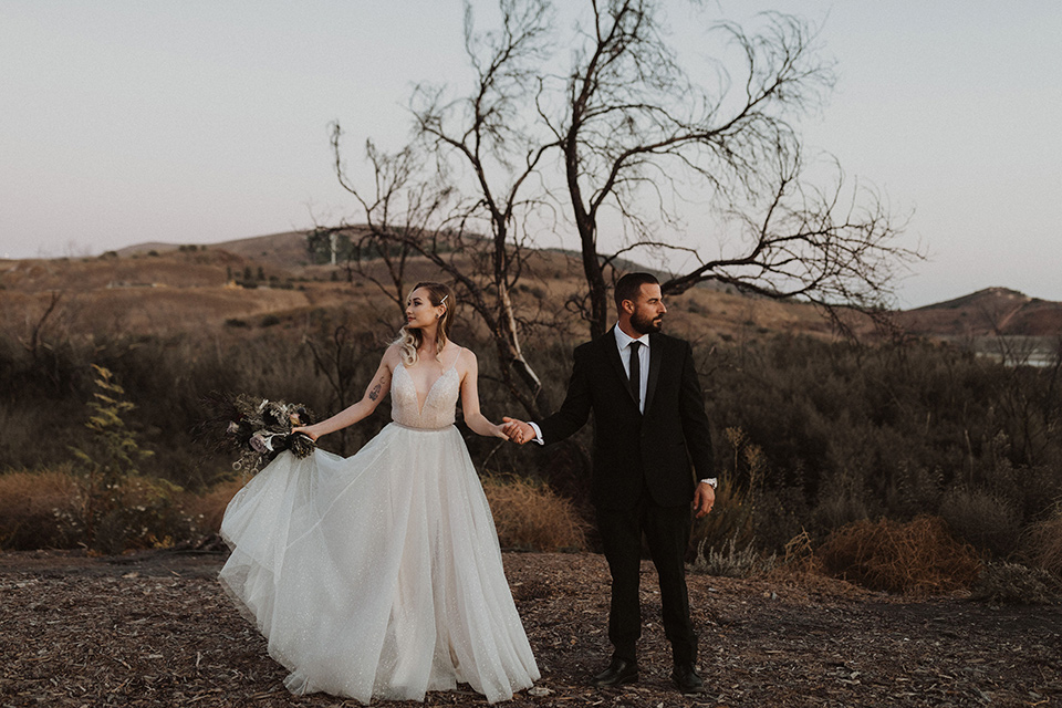  bride in a tulle a line gown with a sweetheart neckline and a crystal bodice and the groom in a black velvet tuxedo and black bow tie sitting at table