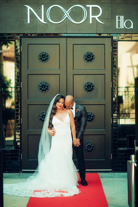  bride in a formfitting gown with a bright red lip and the groom in a black paisley tuxedo with a black bow tie 