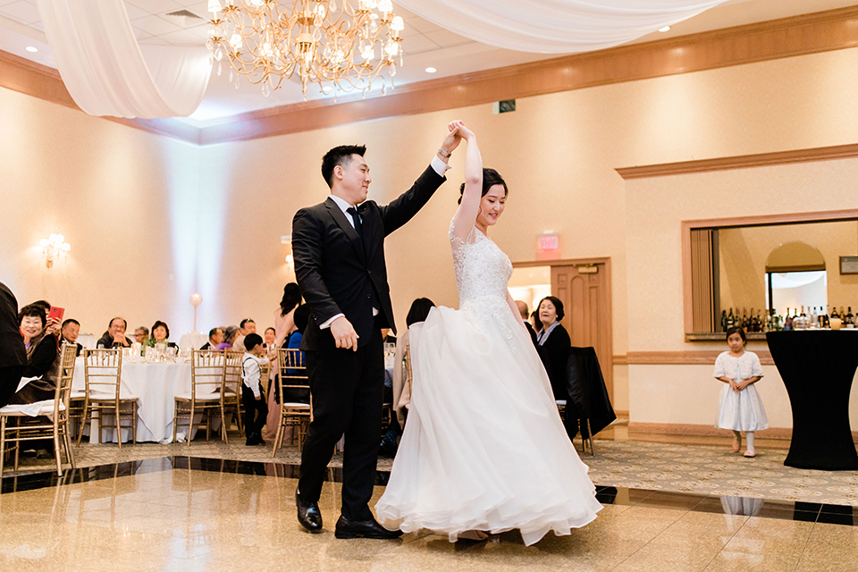  bride in a tulle ballgown with a plunging neckline and a loose bun and groom in a black suit with a black long tie