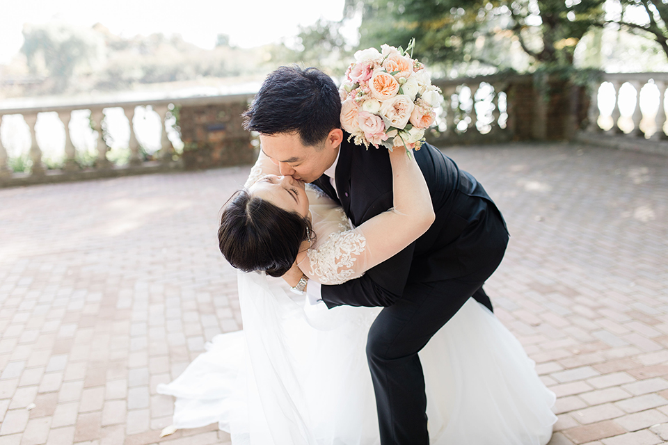  bride in a tulle ballgown with a plunging neckline and a loose bun and groom in a black suit with a black long tie