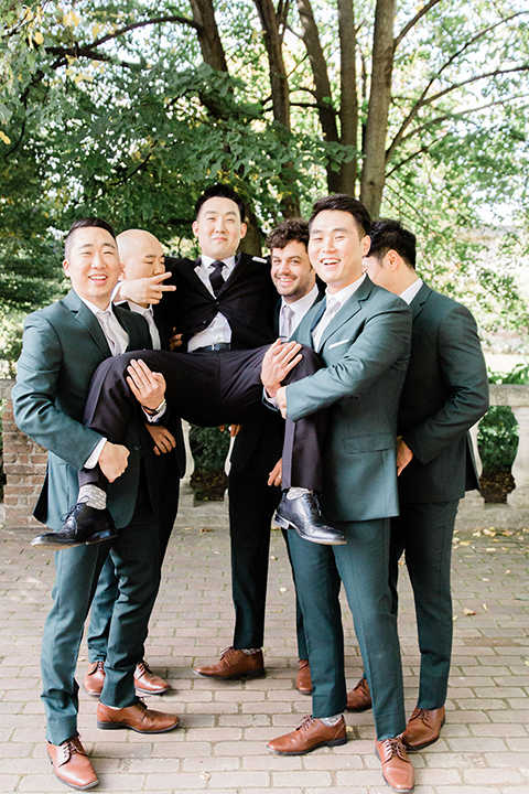  groom in a black suit with a long tie groomsmen in dark black suits 