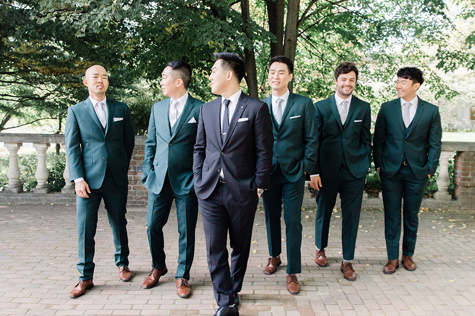  groomsmen in dark green suits and groom in a black suit with a black long tie